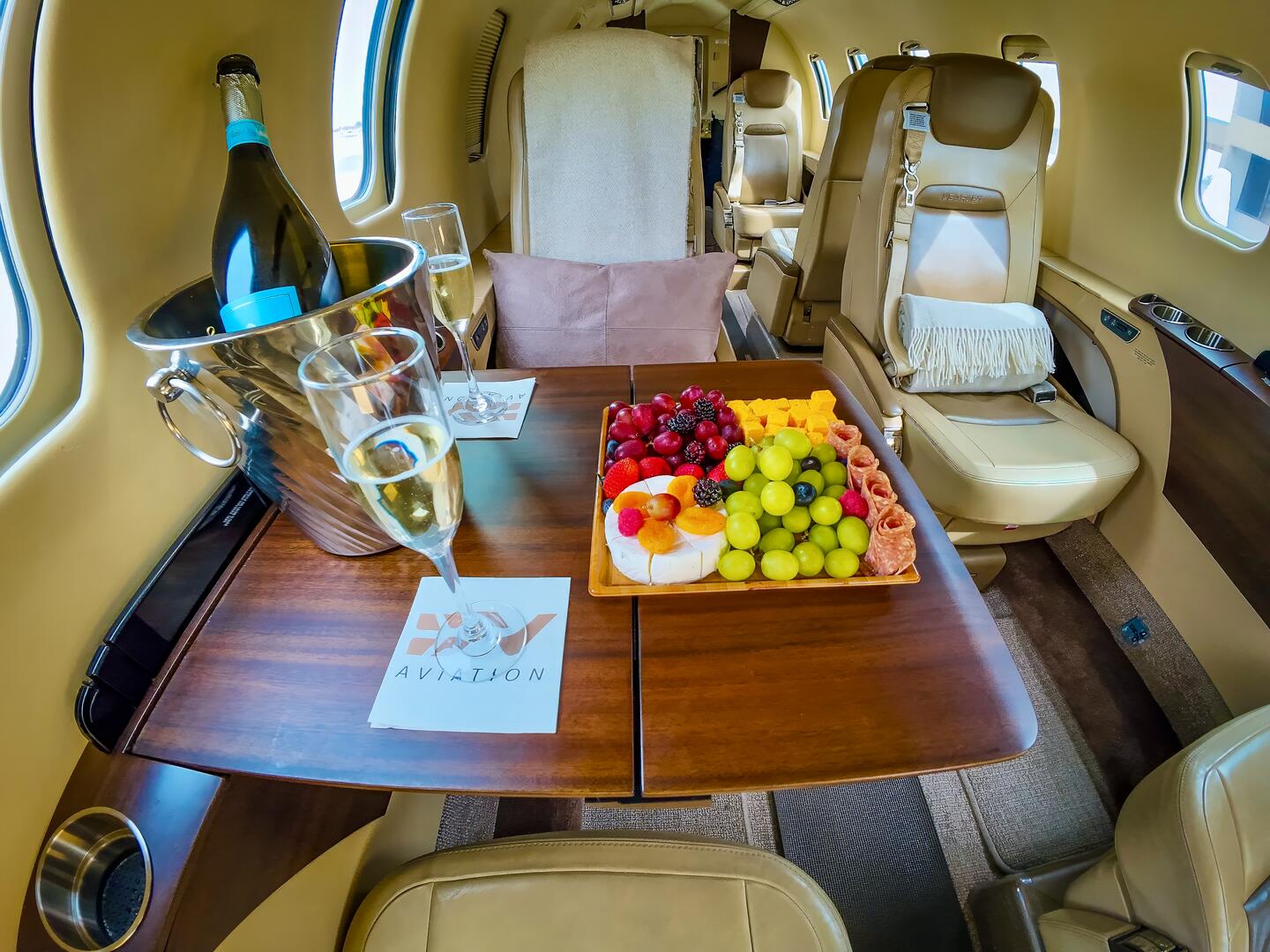 DV Aviation cabin interior — champagne, fresh fruit, and personalized service aboard a private charter